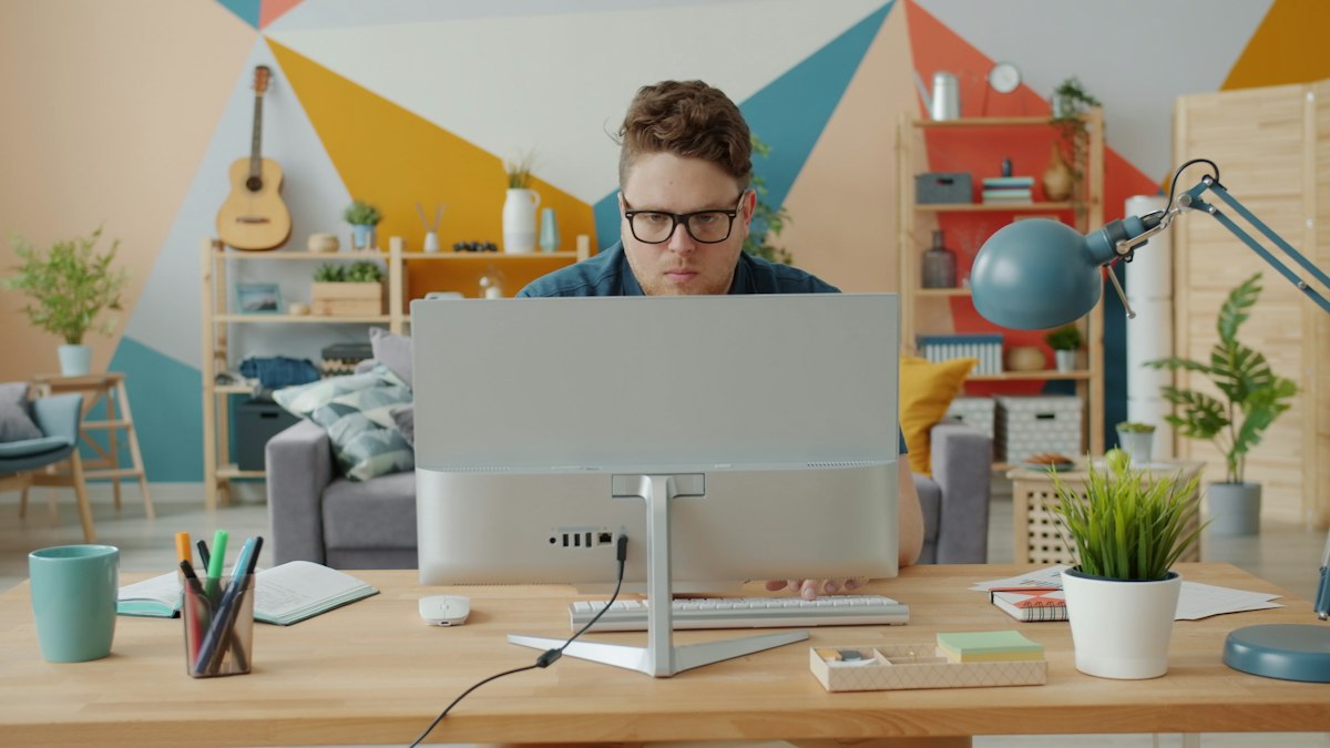 A remote team member working at a desktop computer in a bright home office
